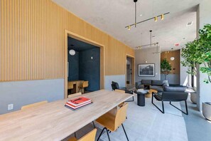 Um espaço de escritório moderno com uma mesa comprida, cadeiras, um sofá e um vaso de planta.