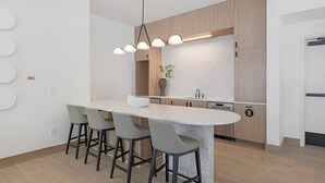 A modern kitchen with a central island, bar stools, a pendant light, and a built-in oven.