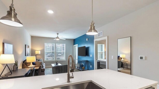 A modern kitchen with a large island, a dining area, and a living space with a TV and seating.