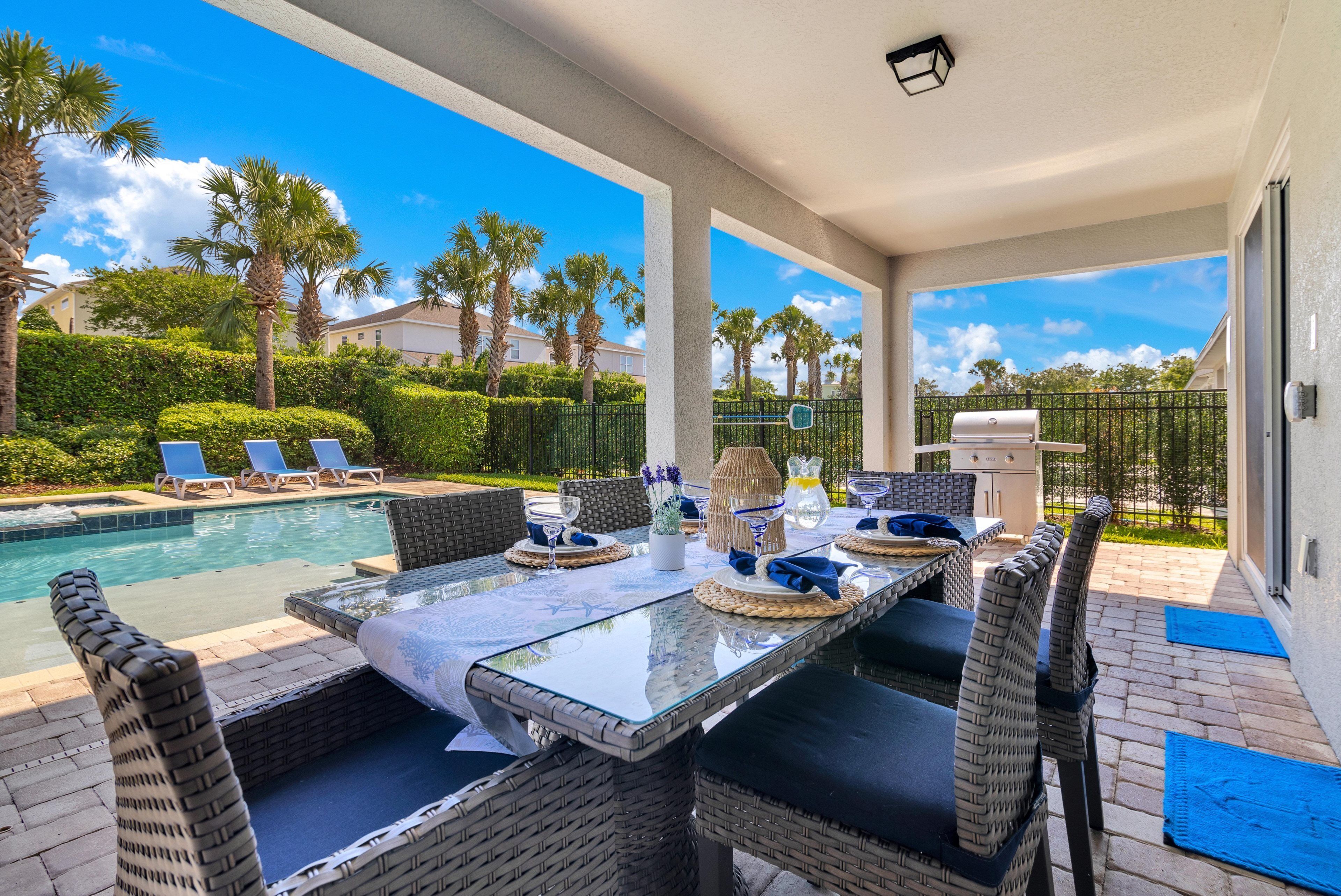 An outdoor dining area with a pool, lounge chairs, and a view of the surrounding landscape.