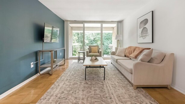 A modern living room with a sofa, coffee table, and a TV mounted on the wall.