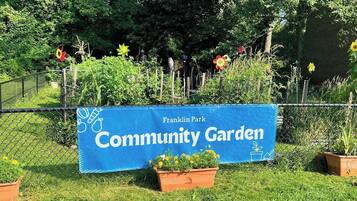 Une banderole bleue sur laquelle on peut lire les mots « Jardin communautaire » et « Parc Franklin », le tout entouré de verdure et de plantes en pot.