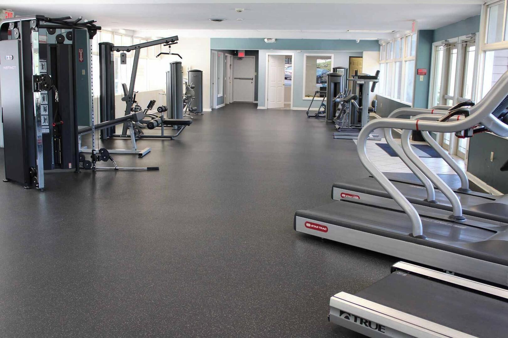 Ein Fitnessstudio mit Laufbändern, Kraftgeräten und Kurzhanteln.
