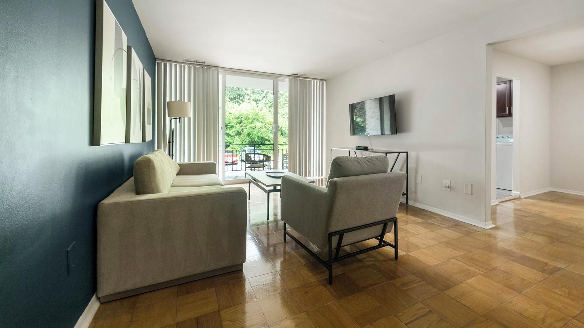 Una sala moderna con sofá, sillón y televisor montado en la pared.