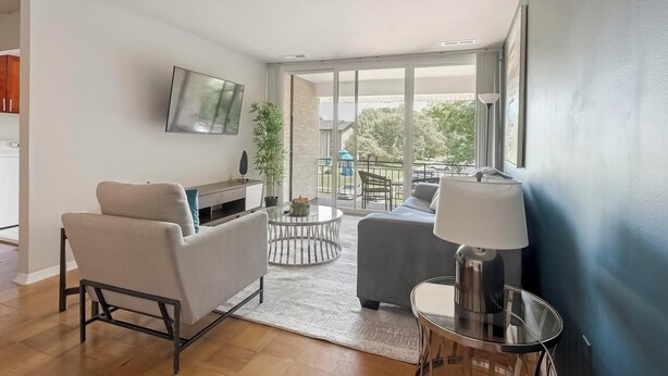 Un salon moderne avec un canapé, une table basse, une lampe et un téléviseur fixé au mur.