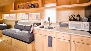 A compact kitchen with a sink, a microwave, and wooden cabinets. - Cozy Tiny Home @ Private Moab Ranch (Moab)