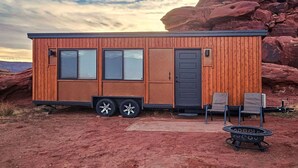 A small, wooden cabin with a sliding door, large windows, and a flat roof. - Cozy Tiny Home @ Private Moab Ranch (Moab)