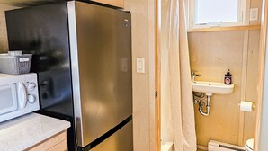 A compact kitchenette with a stainless steel refrigerator, a microwave, and a small sink. - Cozy Tiny Home @ Private Moab Ranch (Moab)
