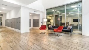 A modern lobby with lockers, a red chair, a black sofa, and a large glass wall.