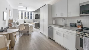 Une cuisine moderne avec des meubles blancs, un four à micro-ondes encastré et une cuisinière. On y trouve également un coin repas avec une table ronde et des chaises.