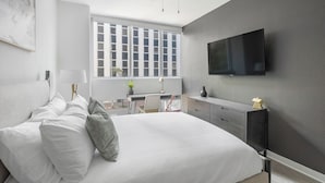 Une chambre moderne avec un grand lit, un bureau et un téléviseur fixé au mur.