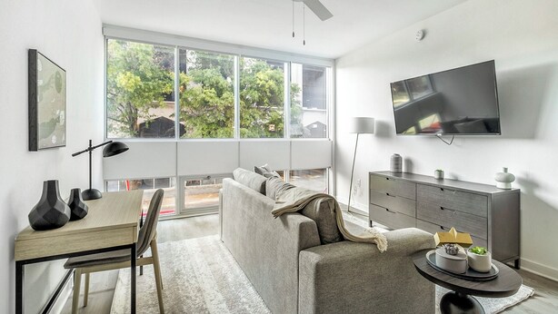 Una sala de estar moderna con un sofá, una mesa de comedor y un televisor montado en la pared.