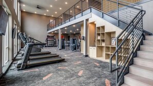 A gym area with treadmills, a mezzanine level, and a staircase.