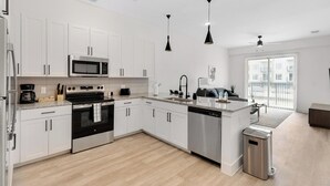A modern kitchen with white cabinets, stainless steel appliances, and a central island.
