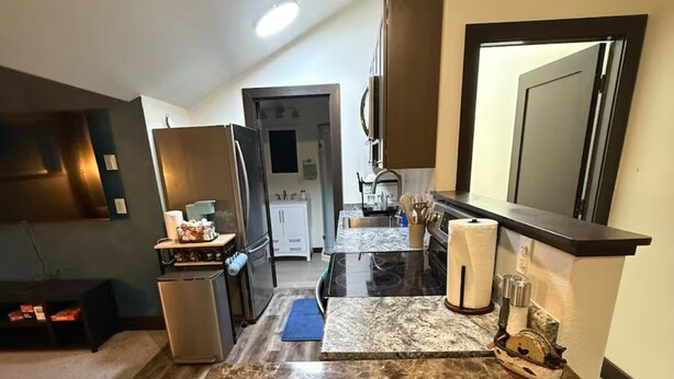 A modern kitchen with a marble countertop, stainless steel appliances, and a view into the dining area.