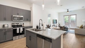 A modern kitchen with grey cabinets, stainless steel appliances, and a granite countertop.
