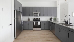 Una cocina moderna con gabinetes grises, electrodomésticos de acero inoxidable y encimera de granito.