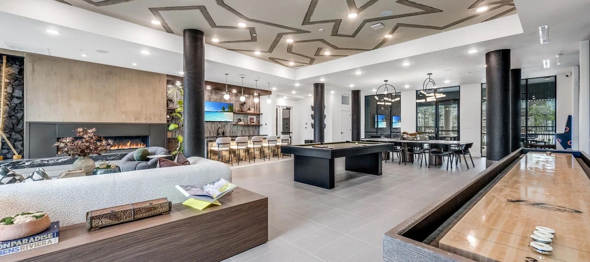 A modern living room with a pool table, a fireplace, and a bar area.