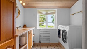 A compact laundry room with a window, a washing machine, a toilet, and a sink. - Beautiful home in Tarm with house sea view (Tarm)