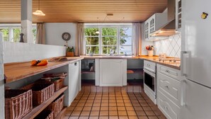 A compact kitchen with a wooden ceiling, white cabinets, and a tiled floor. - Beautiful home in Tarm with house sea view (Tarm)