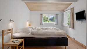 A bedroom with a bed, a chair, a desk, a TV, and a window with curtains. - Beautiful home in Tarm with house sea view (Tarm)