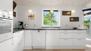 A modern kitchen with white cabinetry, a Bosch oven, a window with a view of greenery, and pendant lighting. - Beautiful home in Tarm with WiFi (Tarm)