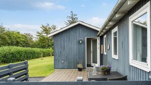 A blue building with a wooden deck, a potted plant, and a glass table. - Beautiful home in Tarm with WiFi (Tarm)