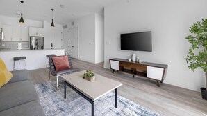 A modern living room with a sofa, coffee table, and a TV mounted on the wall. - Landing | Stunning 1BD, Clubhouse, Gym (Denton)