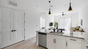 A modern kitchen with white cabinetry, a granite countertop, and black pendant lights. - Landing | Stunning 1BD, Clubhouse, Gym (Denton)