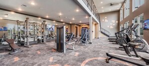 A gym with various exercise equipment, a mirrored wall, and a staircase leading to an upper level.