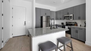 Une cuisine moderne avec des meubles gris, des appareils en acier inoxydable et un plan de travail en granit.