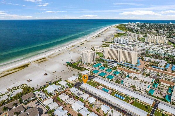 An aerial view of a coastal resort area with beachfront properties, a marina, and a large hotel complex. - Charming Beachside Retreat - Aloha Kai #18 - Roelens (Siesta Key)
