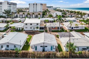 A coastal residential area with white houses, palm trees, and a beach in the background. - Charming Beachside Retreat - Aloha Kai #18 - Roelens (Siesta Key)