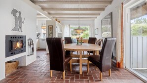 A dining area with a round table, black chairs, a fireplace, and a view of the outdoors. - Beautiful home in Hvide Sande with WiFi (Hvide Sande)
