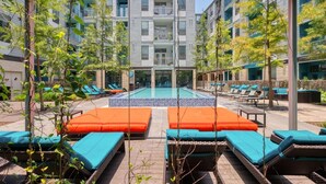 A pool area with lounge chairs and a central pool. - Landing | Chic 1BD, Gym, Rooftop Lounge (San Antonio)