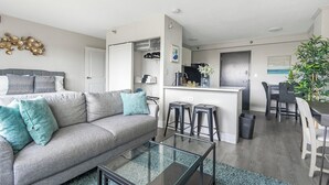 Un appartamento moderno con un divano grigio, un tavolino in vetro, un angolo cottura e una zona pranzo.