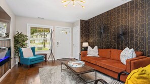 Una sala moderna con sofá, sillón, mesa de centro y un adorno de pared.