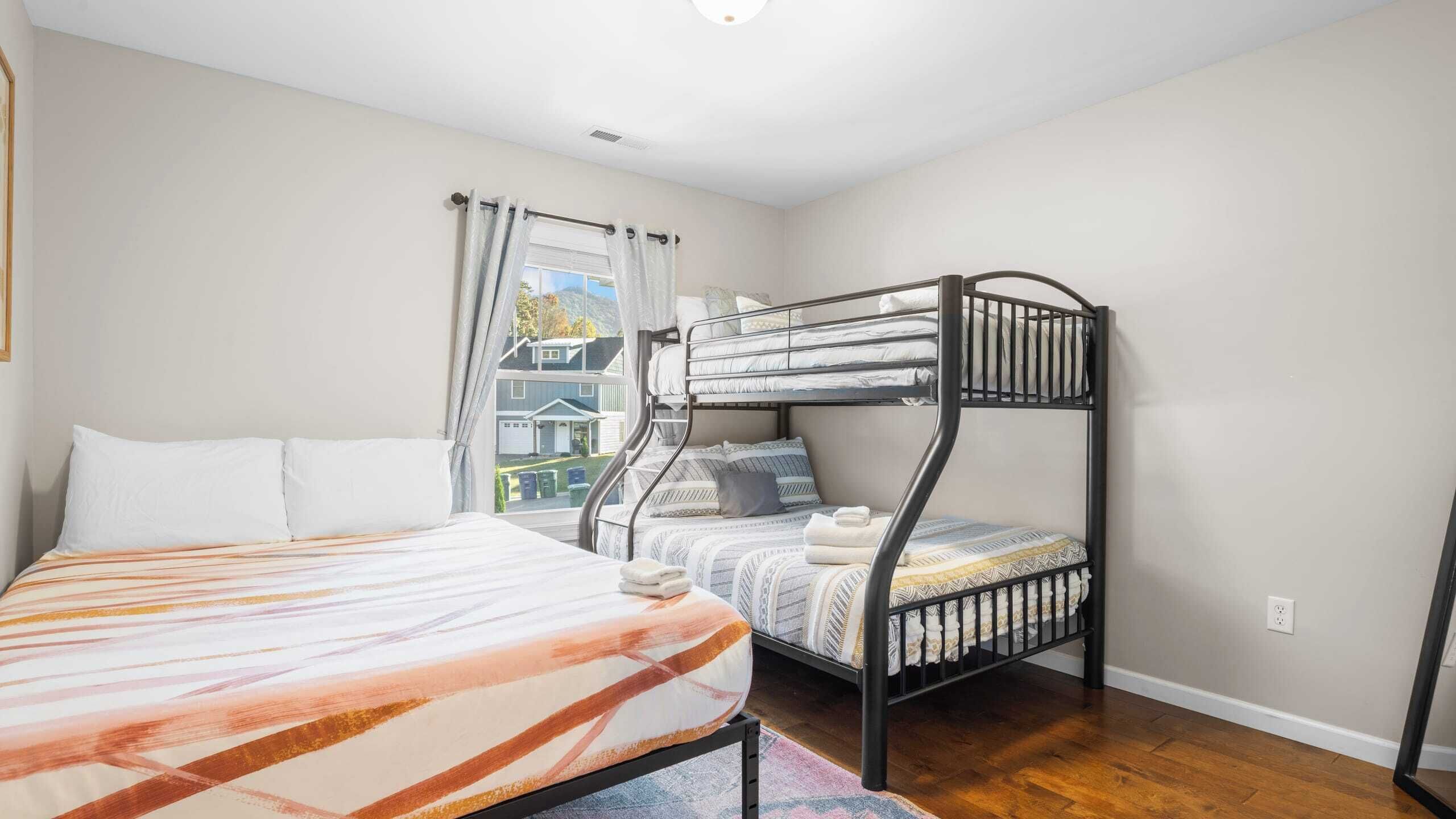 A bunk bed room with a single bed and a bunk bed, both with pillows and blankets.