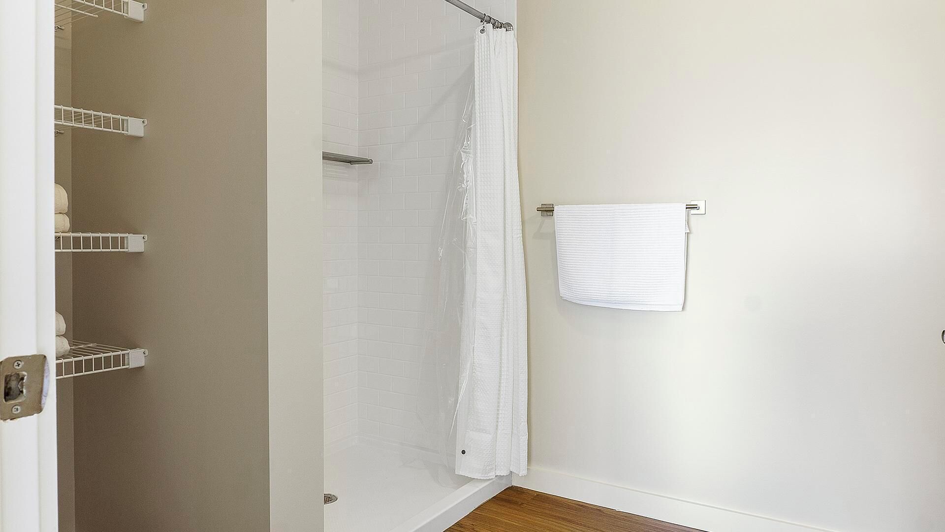 Een badkamer met een douche, een handdoekhouder en een opbergplank.