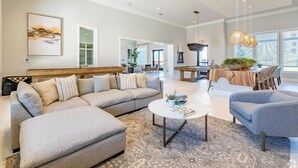 A spacious living room with a sectional sofa, a coffee table, and a dining area with a wooden table and chairs.