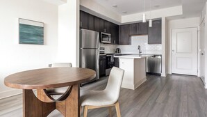 A modern kitchen with dark cabinets, stainless steel appliances, and a white island.