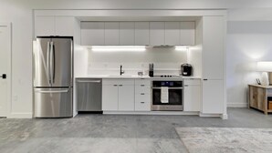 A modern kitchen with stainless steel appliances, white cabinetry, and a built-in oven.