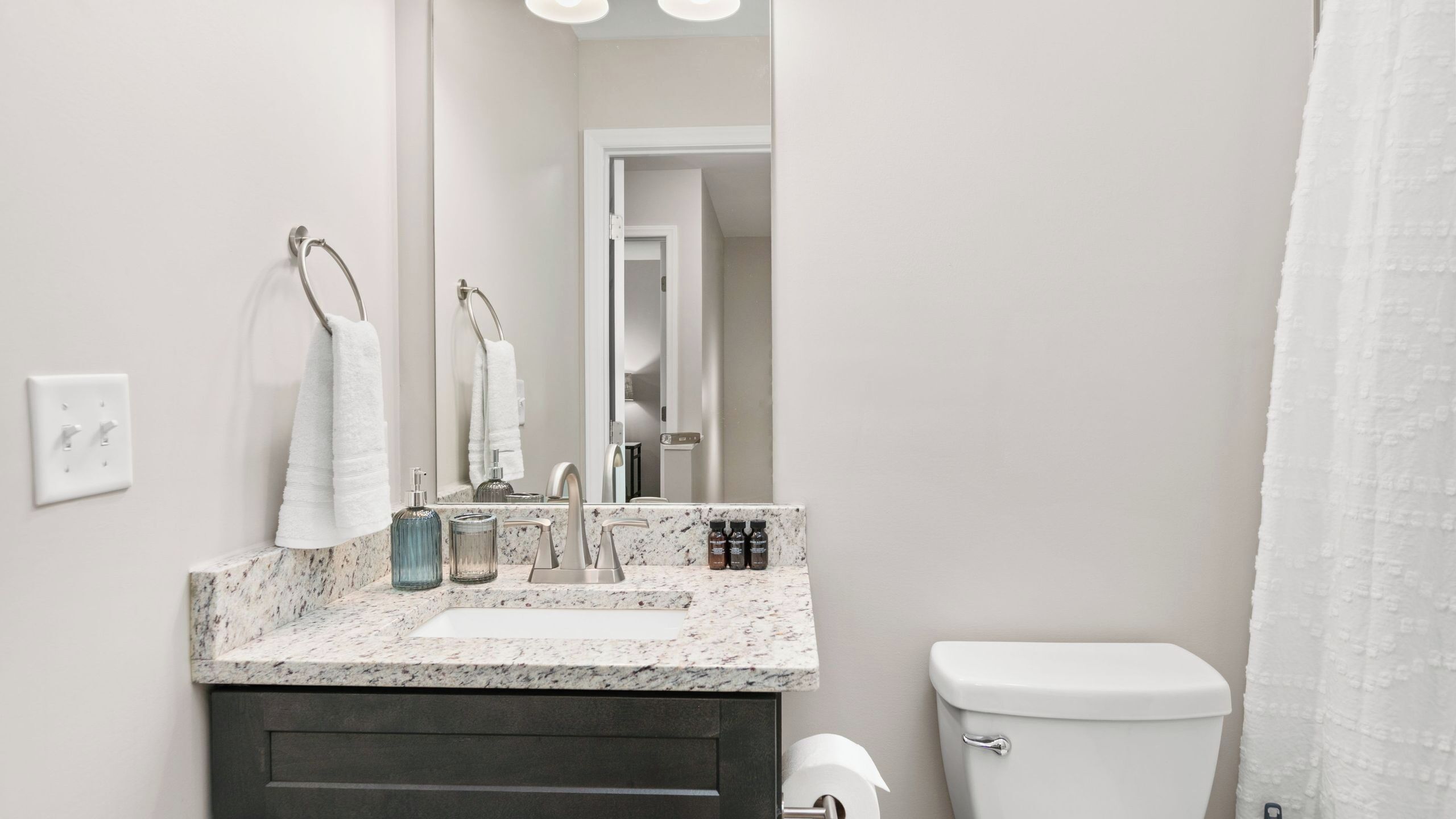 A bathroom with a marble sink, a toilet, and a mirror.