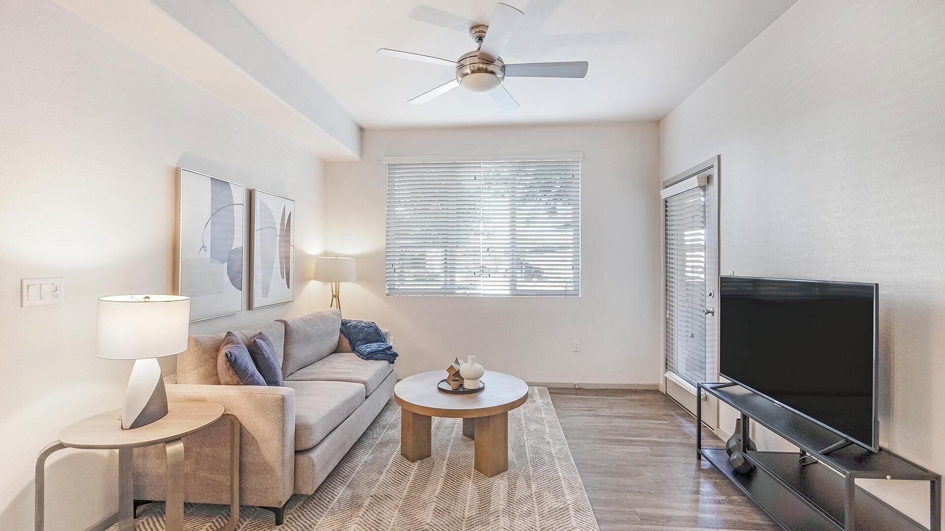 A living room with a sofa, a coffee table, a TV, and a ceiling fan.