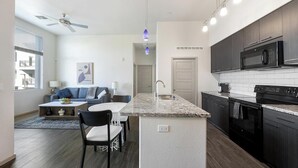 A modern kitchen with dark cabinets, a built-in microwave, and a granite countertop. - Landing | Stylish 1BD, Gym (Glendale)