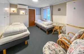 A compact room with two single beds, a small round table, and a wicker chair. - 3 bedroom amazing home in Sjötofta (Sjötofta)