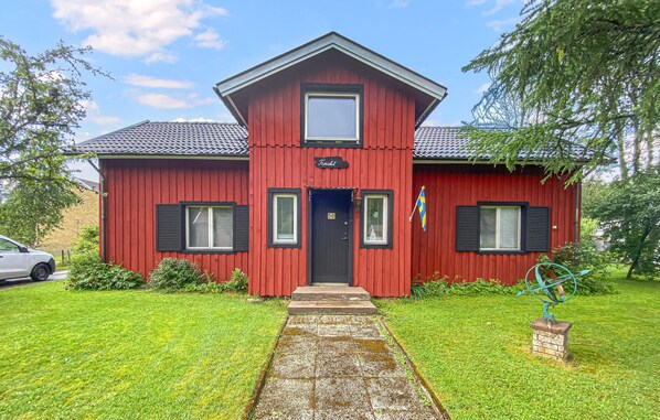 A red two-story house with a black door, numbered 50, and a small flag on the right side. - 3 bedroom amazing home in Sjötofta (Sjötofta)