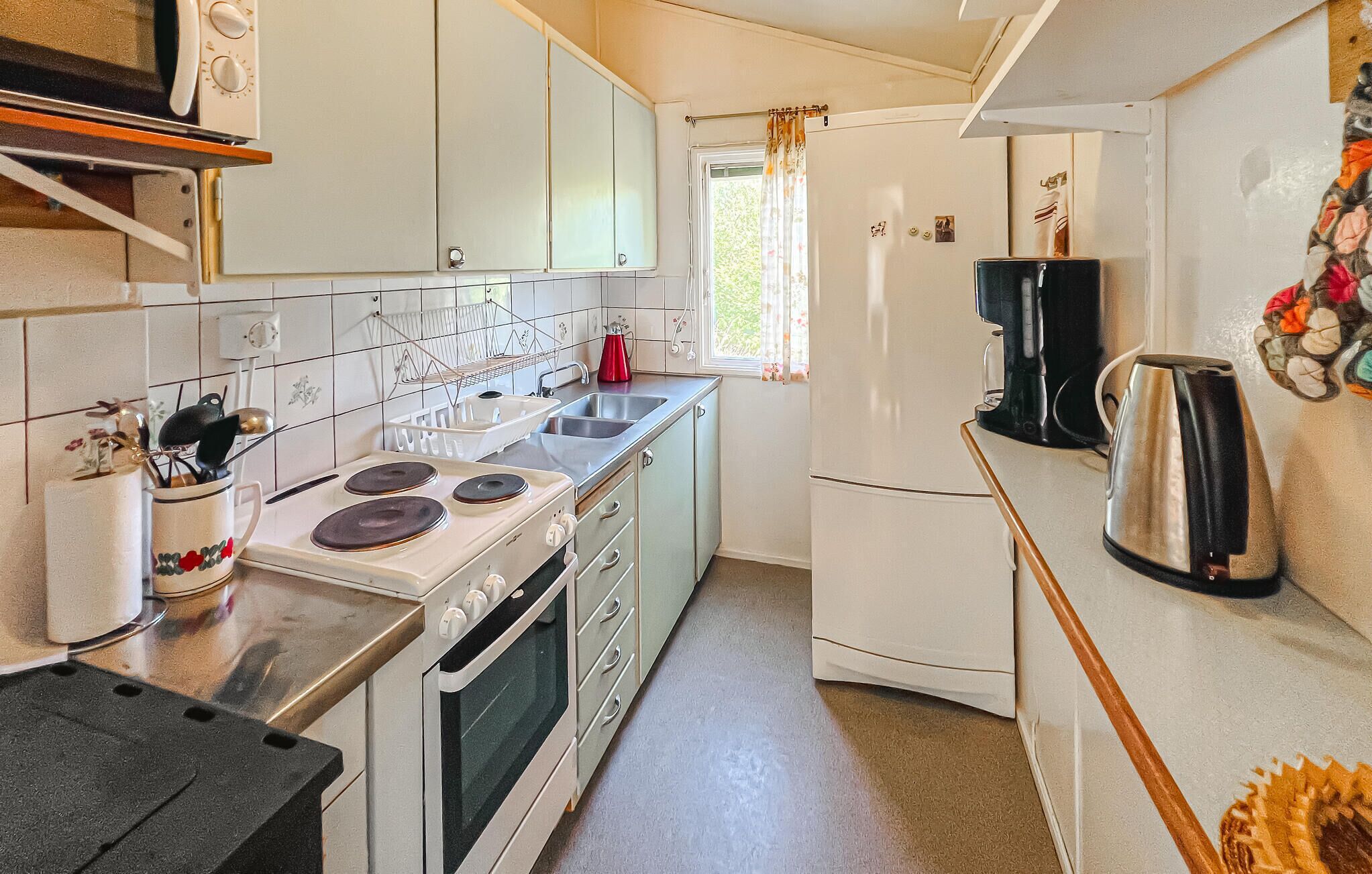 Eine kleine Küche mit Herd, Spüle und Kühlschrank.