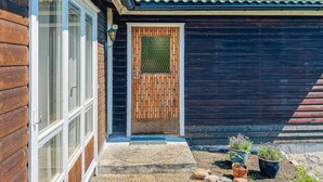 A wooden house with a large window, a wooden door with a window, and a small garden with potted plants. - 1 bedroom beautiful home in Ljungskile (Ljungskile)