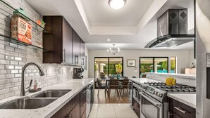 A modern kitchen with a central island, stainless steel appliances, and a view to the dining area.